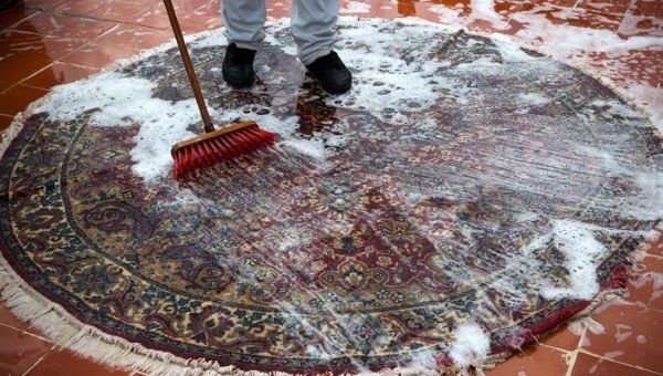 Un homme en train de nettoyer un tapis