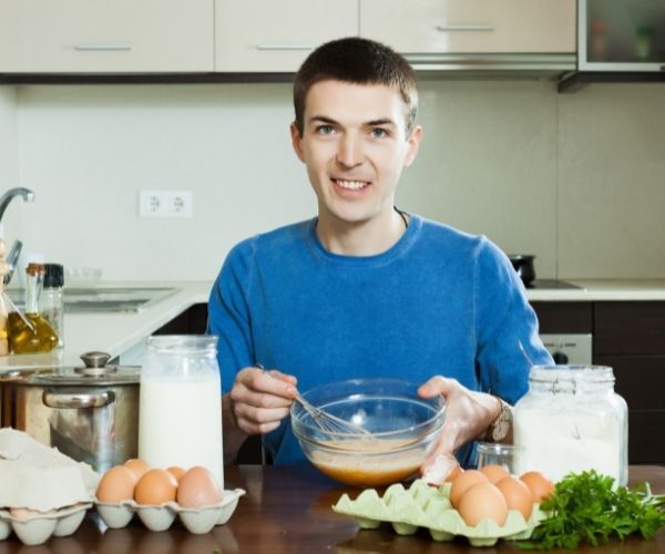 Garçon en train de préparer une omelette dans la cuisine