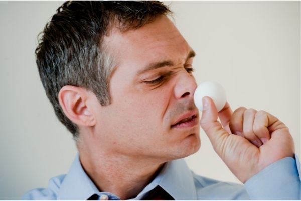 Homme en train de sentir un oeuf