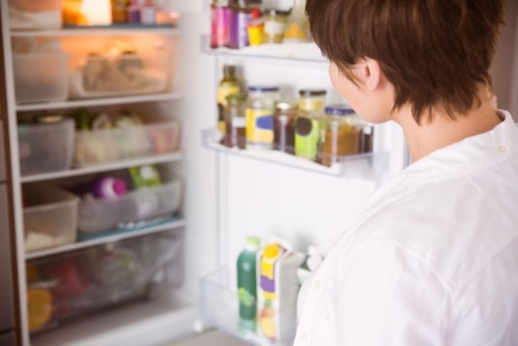une femme regardant à l'intérieur du réfrigérateur