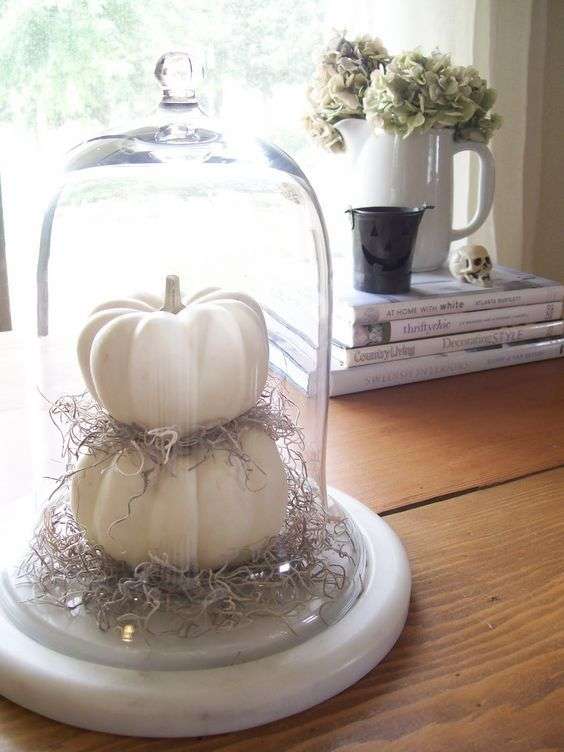 Des citrouilles en blanc superposées dans une dôme en verre pour une touche d'élégance