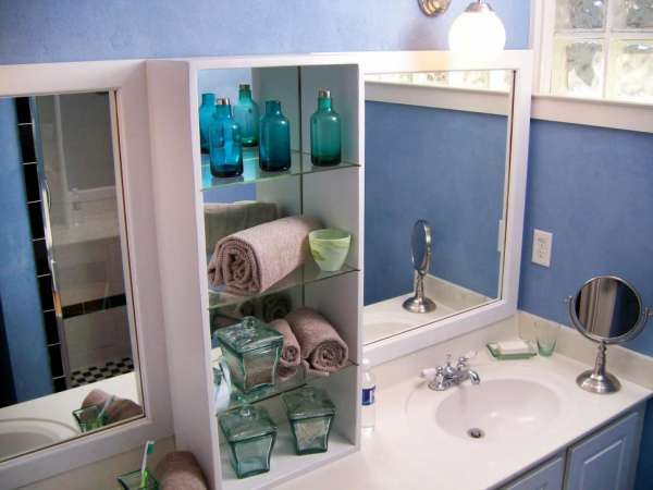 Des étagères en verre avec un dos miroir pour agrandir votre salle de bain