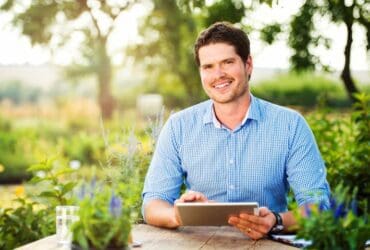 Jeune homme dans un jardin avec une tablette à la main