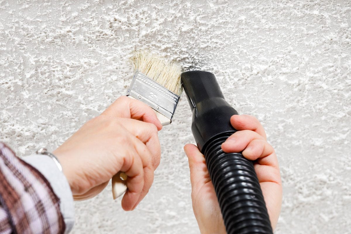 Utilisation d'une brosse pour nettoyer les angles d'un plafond crépi