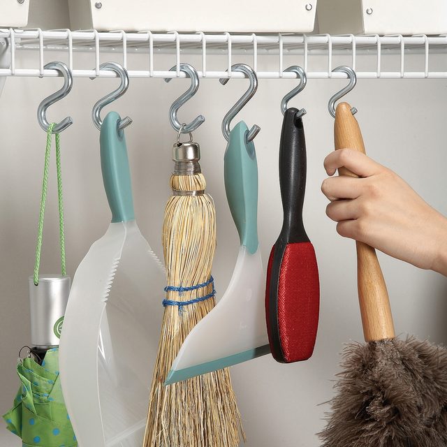 Un crochet en S utilisé pour suspendre un balai à une étagère métallique.