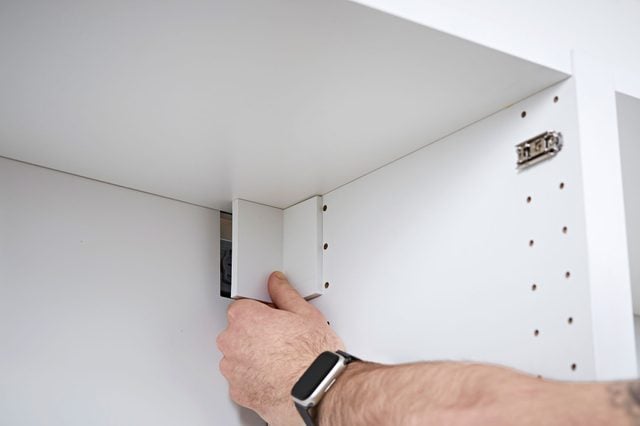 Un cache en plastique est mis en place pour masquer une fixation à l'intérieur d'un meuble.