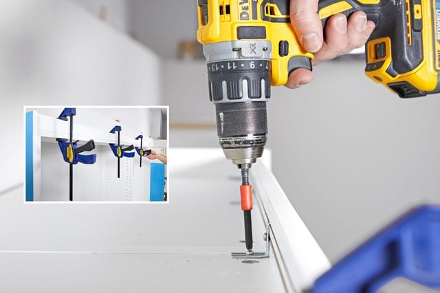 Une personne ajuste une charnière de porte de cuisine avec un tournevis.