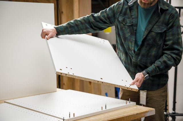 Personne assemblant un caisson de meuble de cuisine blanc.