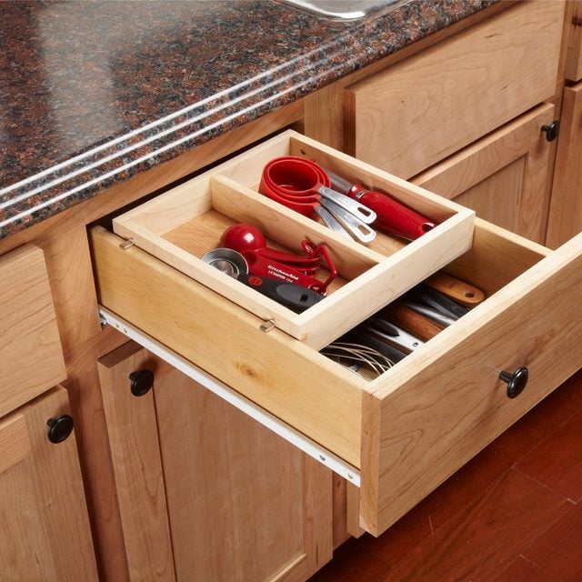 Des bacs de rangement en plastique coupés en deux et vissés à l'intérieur de la porte du meuble sous évier.