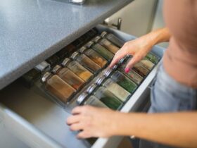 Une main d'une femme en train de ranger les boîtes à épices dans un tiroir de cuisine