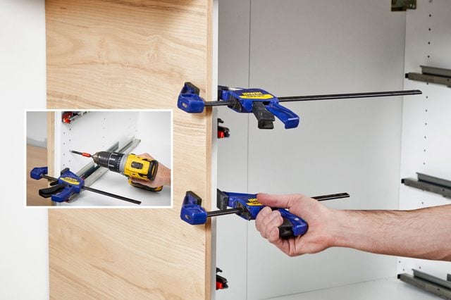 Une personne visse un panneau de finition sur le côté d'un meuble de cuisine.