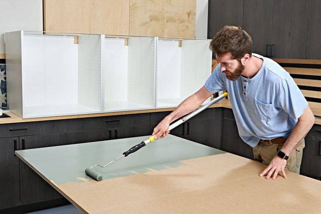 Panneau de bois peint en vert en train de sécher sur des tréteaux.