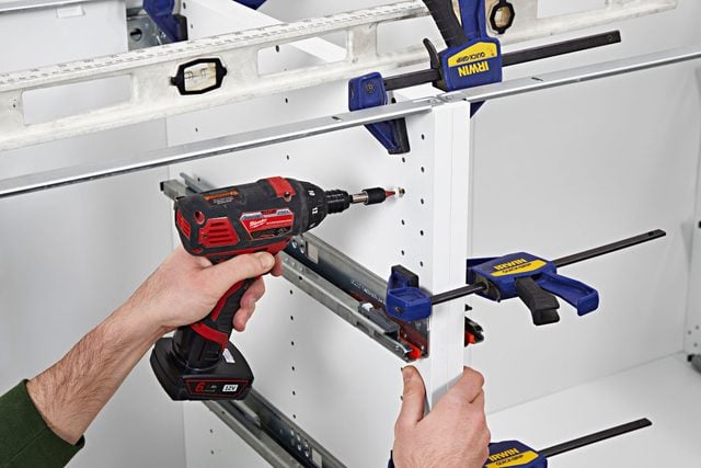 Deux caissons de cuisine sont serrés ensemble avant d'être vissés.