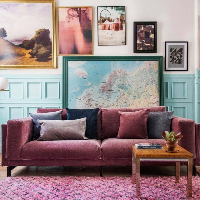 Un canapé rose vif décoré de plusieurs coussins dans un salon coloré.