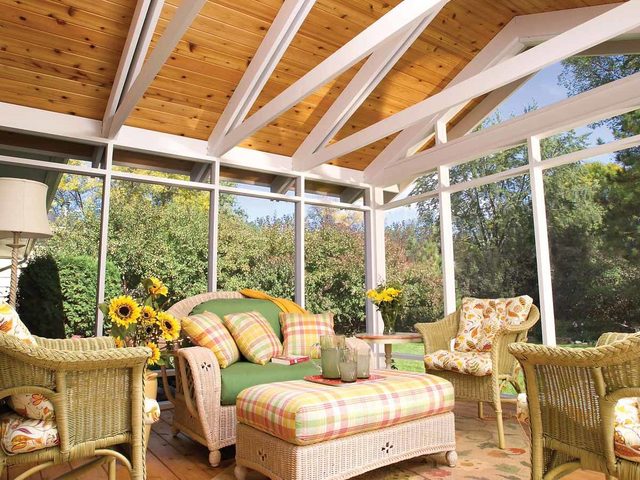 Une véranda confortable avec des meubles en osier et des coussins colorés.