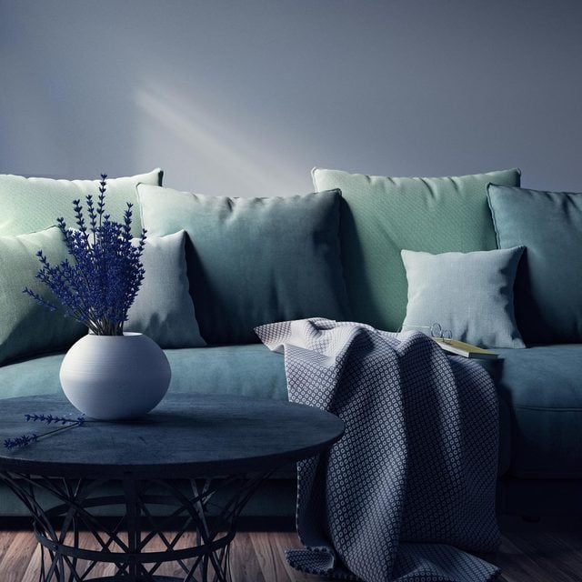 Un canapé bleu-vert avec des coussins superposés de différentes tailles.