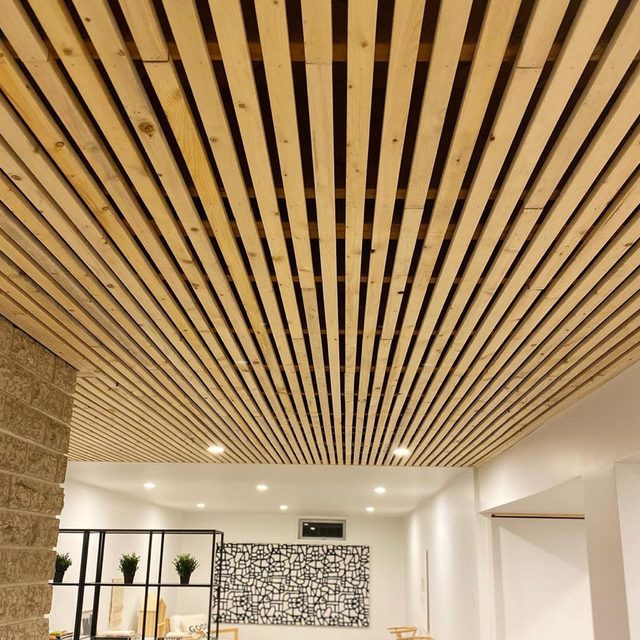 Un plafond moderne en lattes de bois clair dans un sous-sol lumineux.