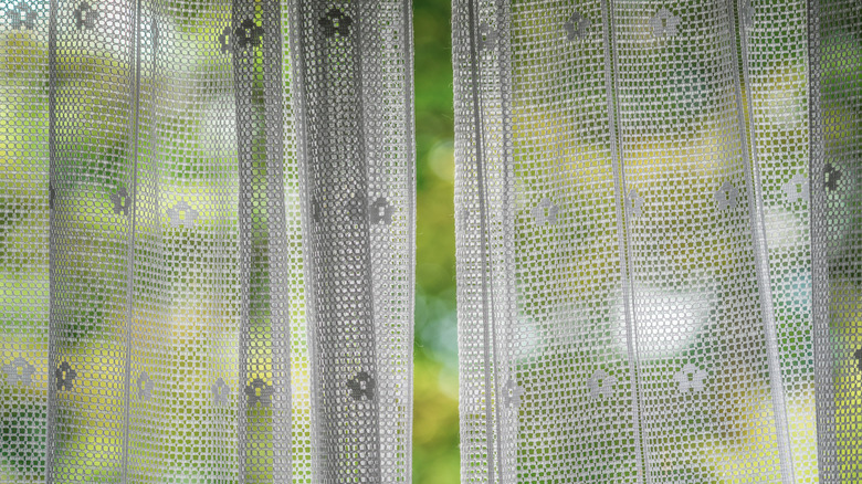 Image 4 : Rideaux en dentelle blancs suspendus à une fenêtre