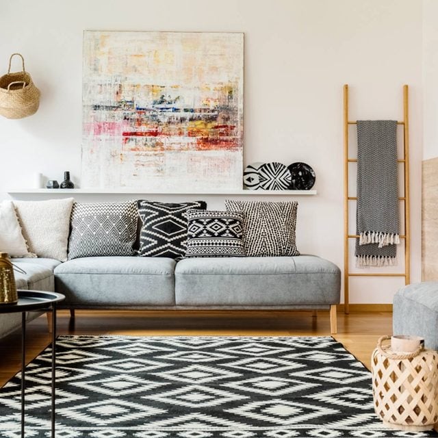 Un canapé gris avec des coussins à motifs et des cadres colorés au mur.