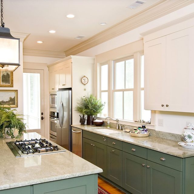 Une cuisine moderne avec des meubles verts surmontés d'une large moulure décorative.