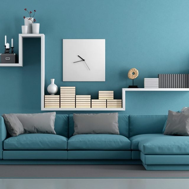 Un canapé turquoise avec des coussins, posé contre un mur de la même couleur.