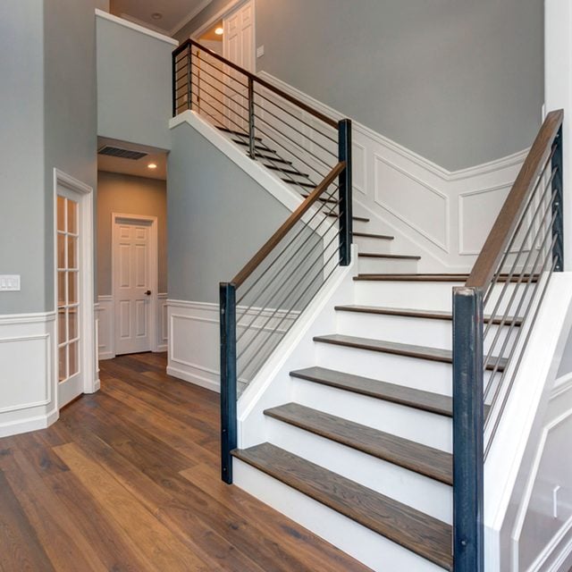 Un escalier moderne avec une rampe aux lignes horizontales en bois et métal.