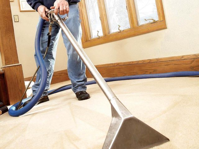 Une personne utilise une shampouineuse pour nettoyer une moquette.
