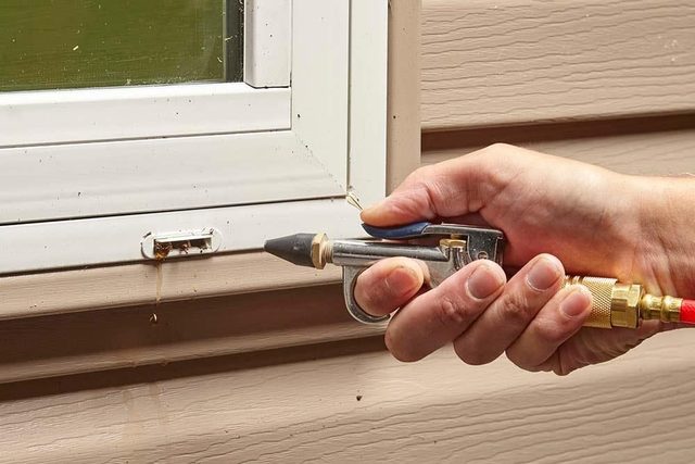 Gros plan sur le nettoyage des petits trous d'évacuation d'une fenêtre.