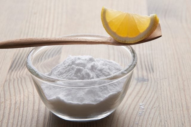 Un bol de fécule de maïs avec une cuillère et une tranche de citron.