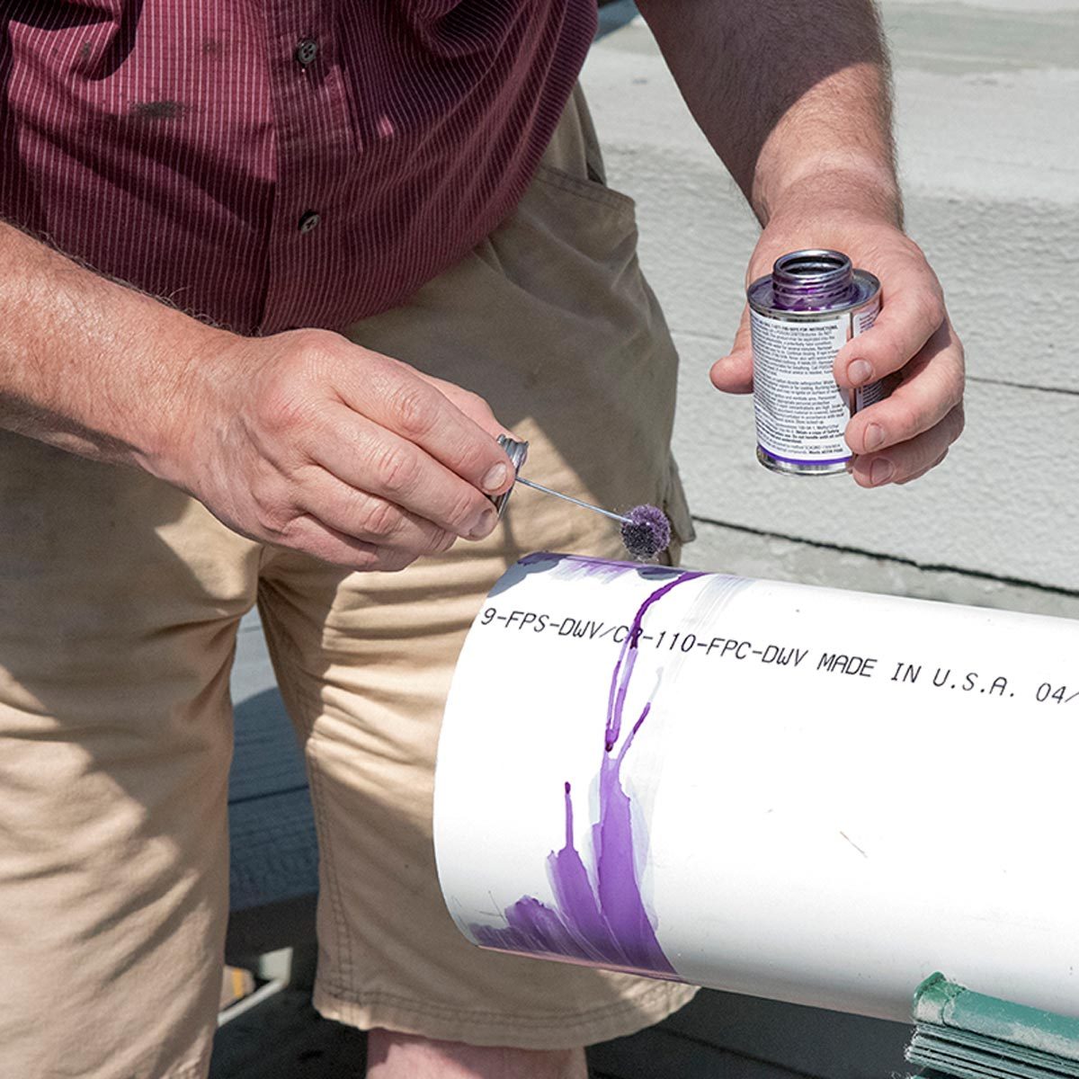 Une personne applique un produit violet au pinceau sur un tube en PVC blanc.