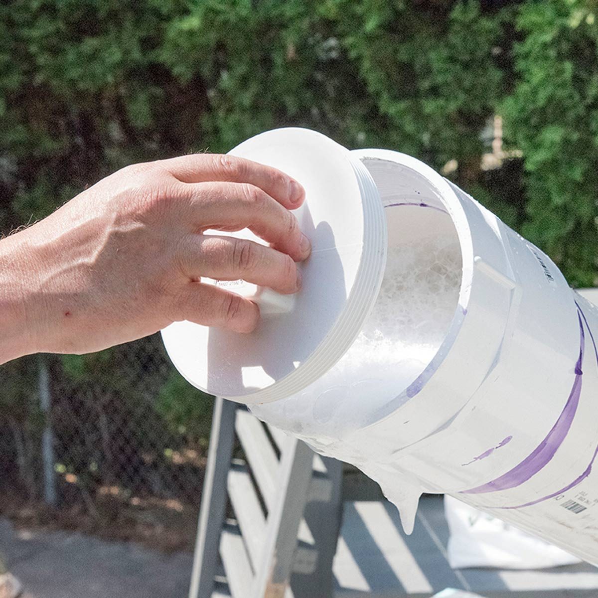 Une main visse le bouchon sur le tube, de la mousse de savon déborde.