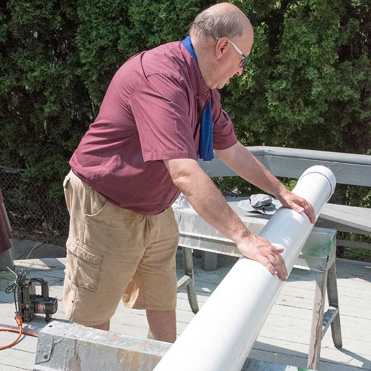 Un homme fait rouler le tube en PVC posé sur des tréteaux pour agiter l'intérieur.