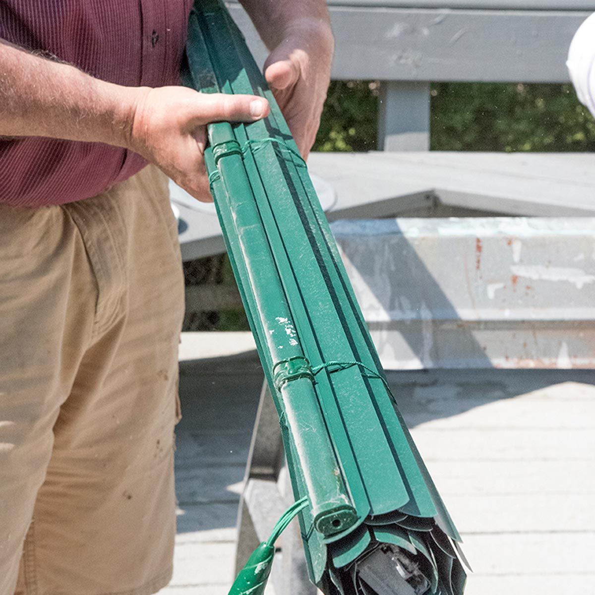 Un store vénitien vert est enroulé en un rouleau compact.