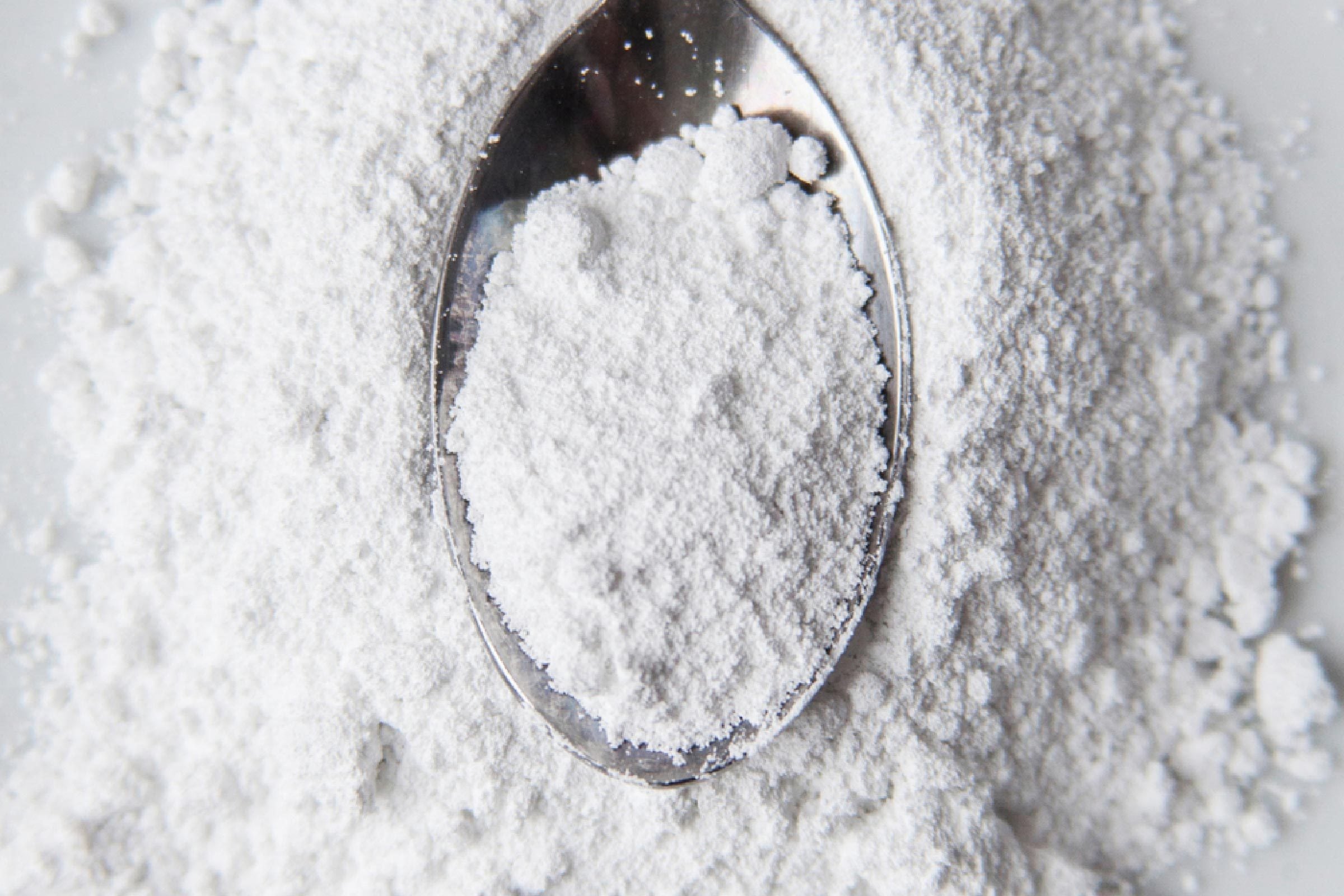 Une cuillère remplie de poudre blanche, type fécule de maïs.