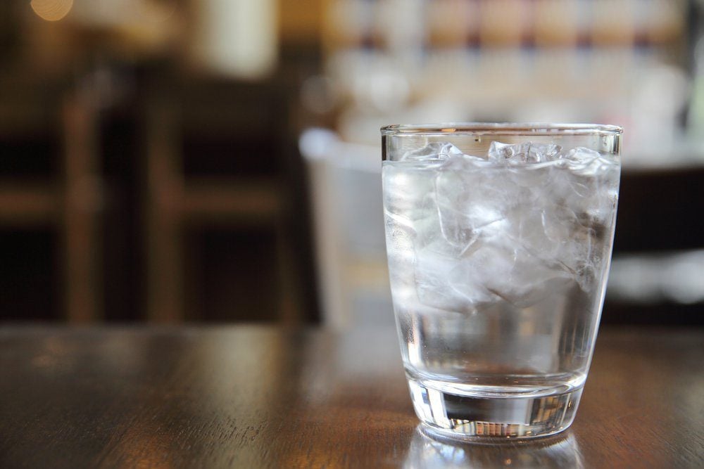 Un verre d'eau glacée posé sur une table en bois.