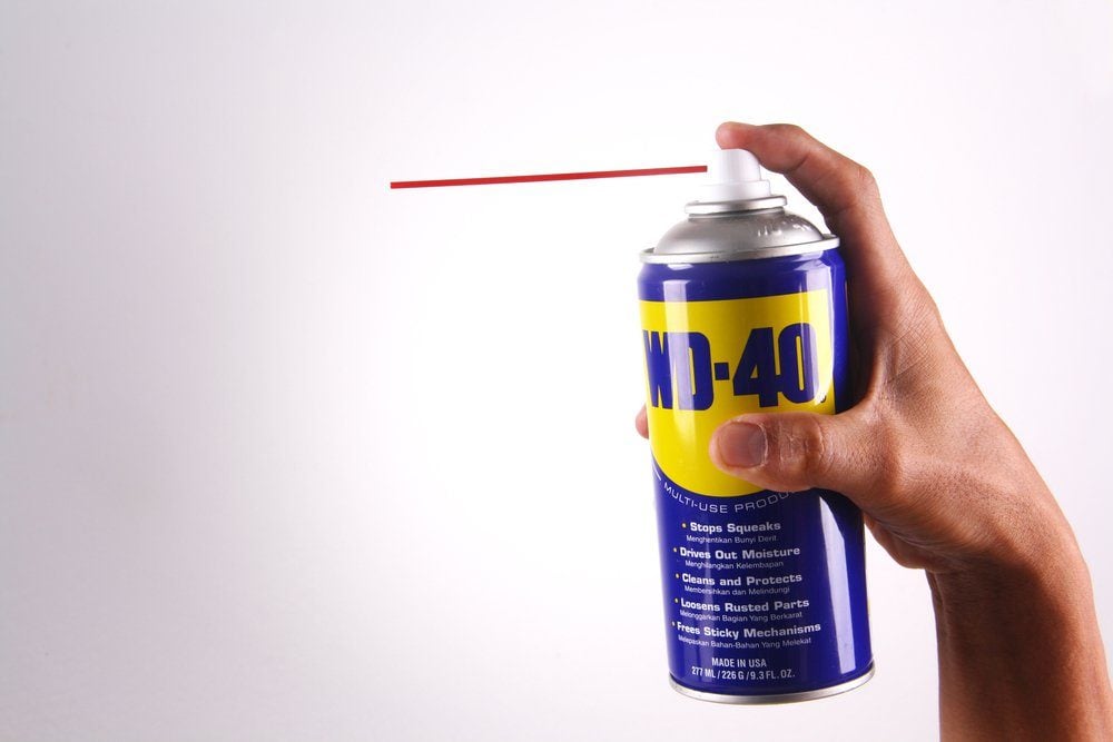Une main tenant une bombe de WD-40 en train de pulvériser.