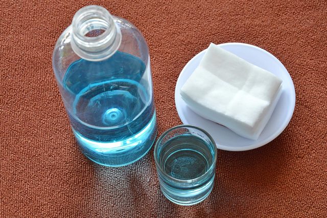 Une bouteille de liquide bleu avec un chiffon sur une assiette.