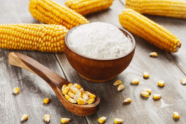 Un bol de fécule de maïs avec des épis de maïs à côté.
