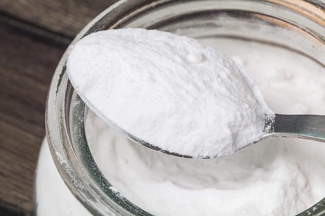 Une cuillère sortant d'un pot de poudre blanche.