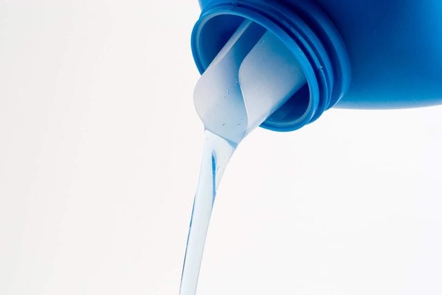 Une bouteille bleue versant un liquide transparent.