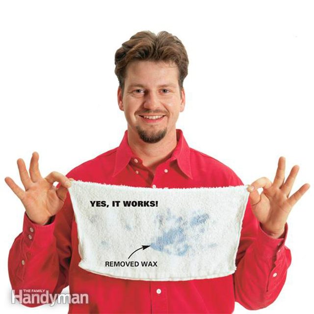 Un homme montre un chiffon blanc avec une tache de cire retirée.