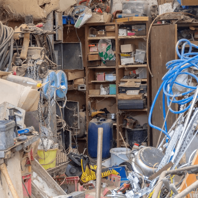 Un établi de bricolage très en désordre, rempli d'outils, de matériaux et d'équipements empilés.