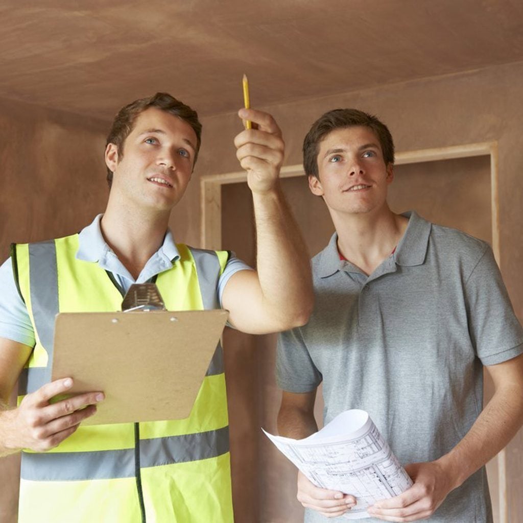 Deux hommes en tenue de chantier examinent des plans.