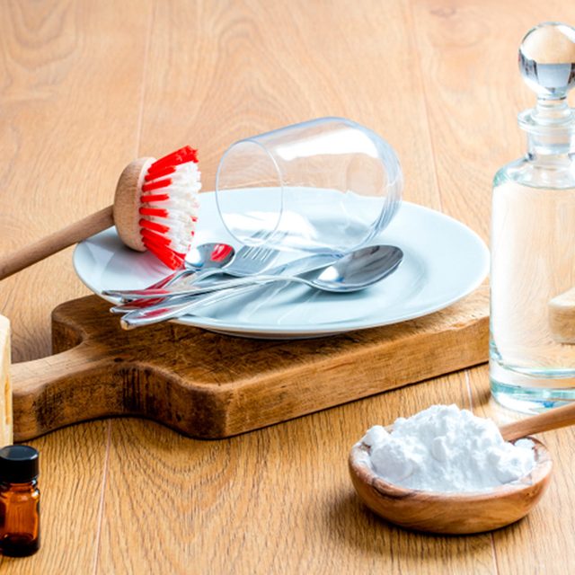 Des produits de nettoyage naturels comme du bicarbonate de soude et une brosse sur une planche en bois.