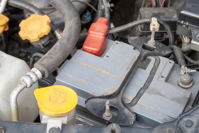 Gros plan sur une batterie de voiture dans un compartiment moteur.