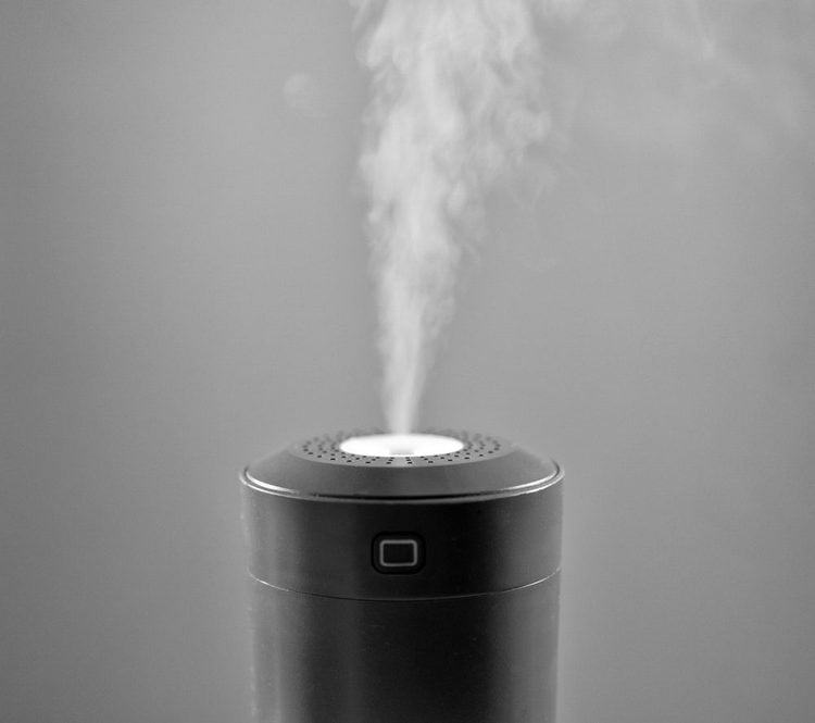 Un humidificateur noir diffuse une fine brume dans l'air.