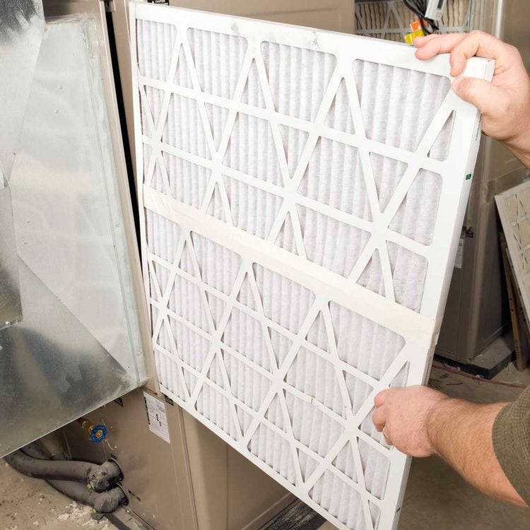 Une personne retire un filtre de fournaise usagé.