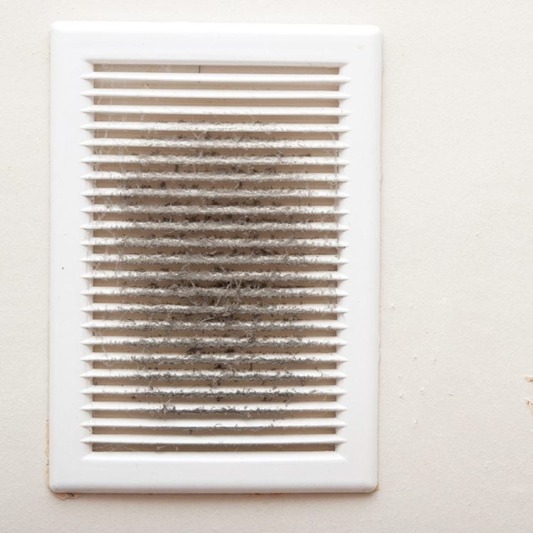 Une grille d'aération blanche couverte de poussière.
