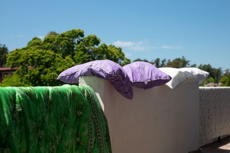 coussins et couverture séchant au soleil sur un mur