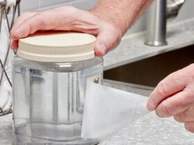 Une personne décolle une étiquette d'un bocal transparent dans une cuisine.